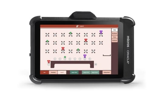 A MICROS Tablet 722P handheld terminal in a protective bumper, showing a table management screen